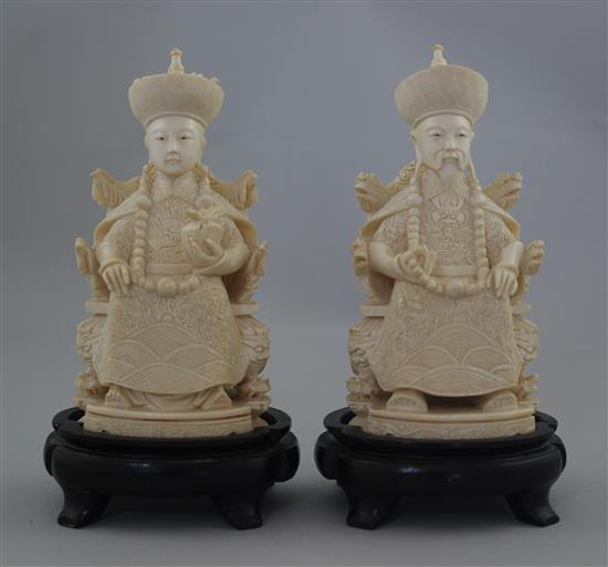 A pair of Chinese ivory seated figures of an emperor and empress, first half 20th century, 13.5cm excl. the wood stands